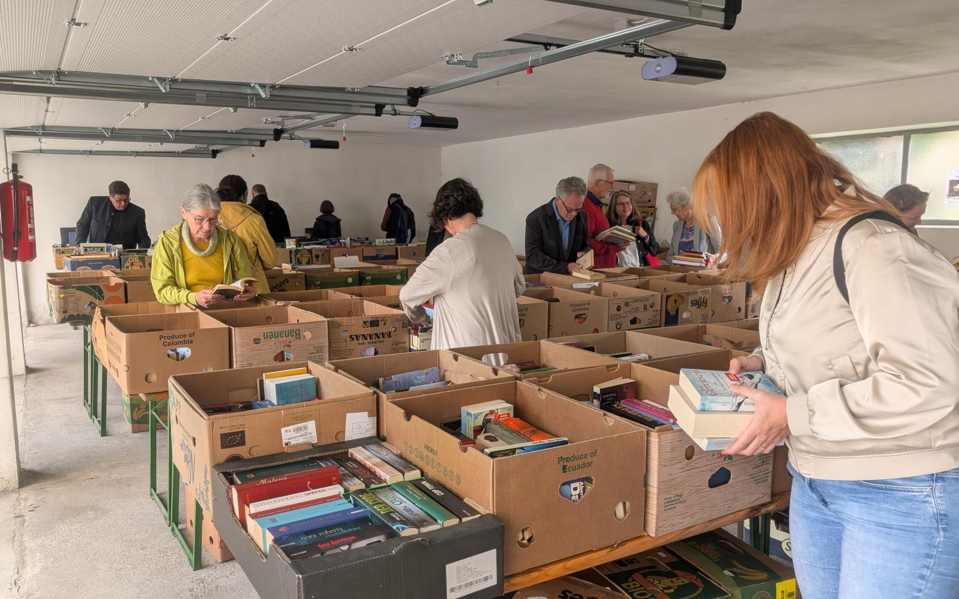 Menschen stöbern in Bücherkisten